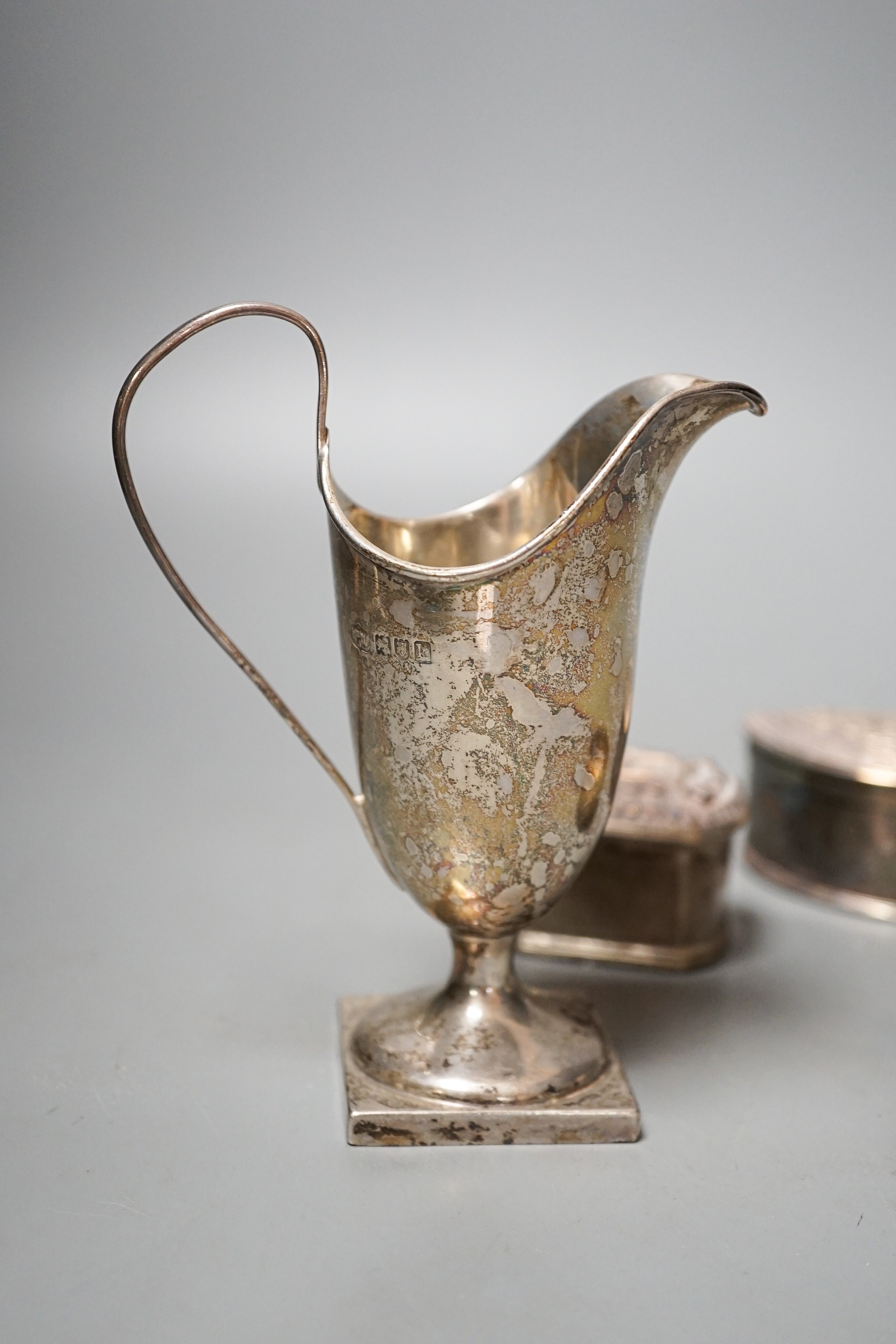 A Edwardian silver helmet shaped cream jug, Mappin & Webb, London, 1905, 13.1cm and three Indian white metal items including two lidded pots.